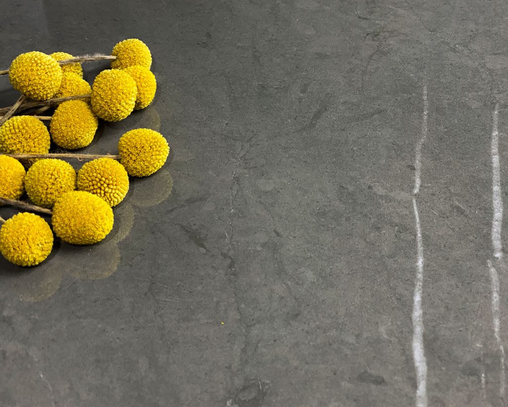 Copertina collezione Marmi Pregiati Pietra Grey con fiori finti gialli per accedere alla pagina della serie